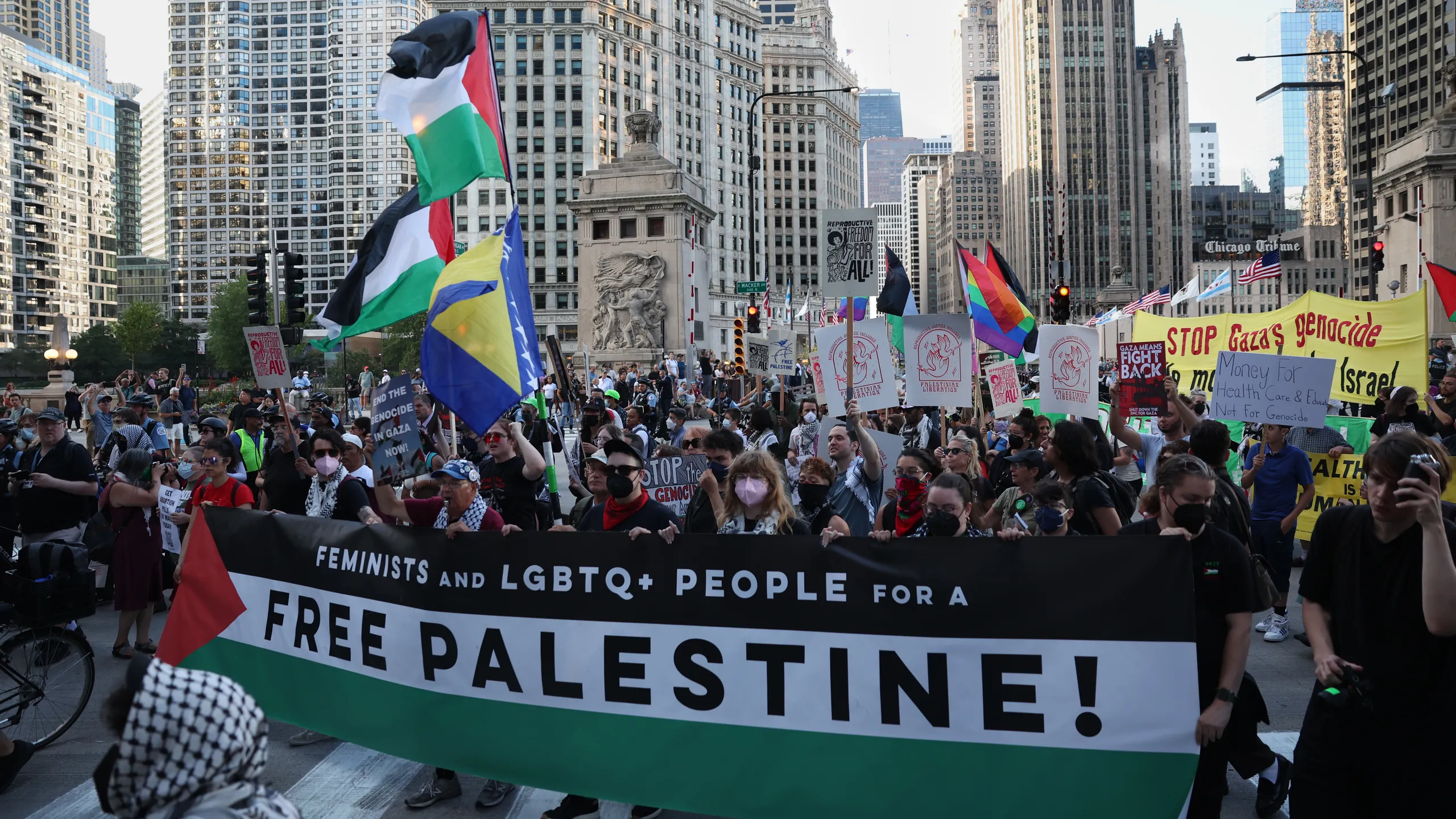 A large crowd of protesters holding signs and Palestinian flags marching