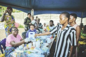 A medical volunteer, Nimi Oruambo (left), handing over medication to a beneficiary during the event