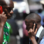 People use mobile phones in Nairobi, Kenya. There are about 700m sim cards in Africa.