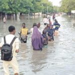 People wading through the flooded  Gwange area as a result of downpour in Maiduguri, yesterday