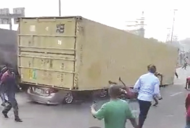Fallen container with Toyota Camry underneath.
