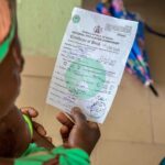 POV photograph of a woman holding and reading a birth certificate