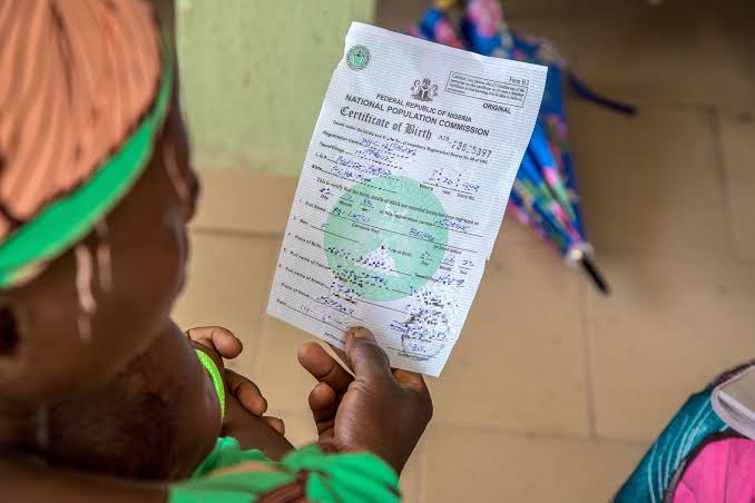 POV photograph of a woman holding and reading a birth certificate