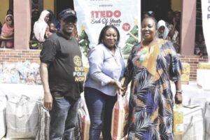 Elusakin and Past President, Ifeoma Anieze Corona presenting a bag of rice to a staff of the school