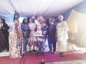 Mr. and Mrs. Adebote (middle) with friends and family members cutting her 60th birthday cake