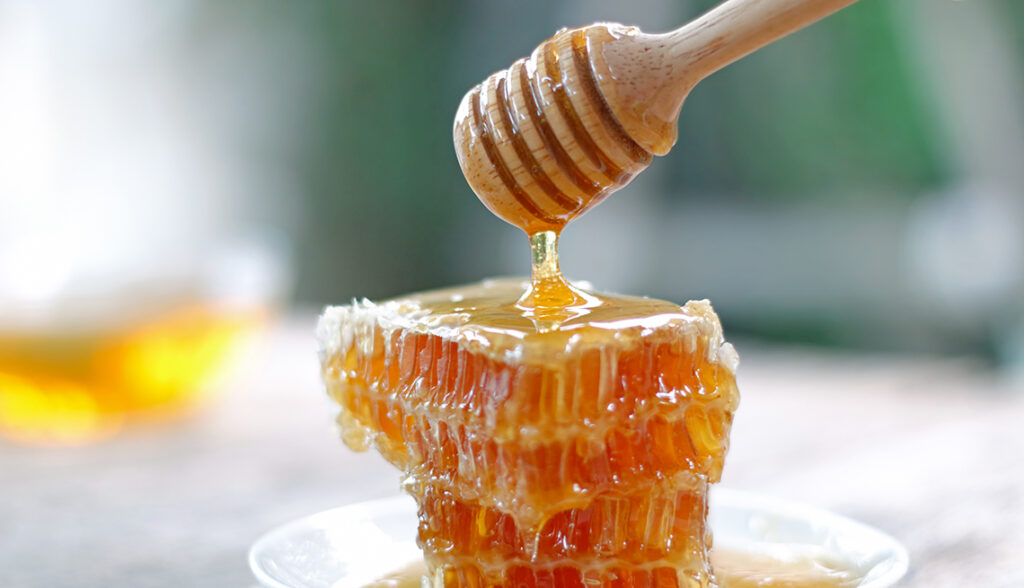 Honey dipper and honeycomb on table