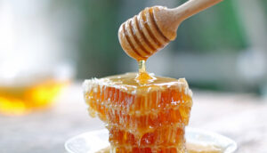 Honey dipper and honeycomb on table