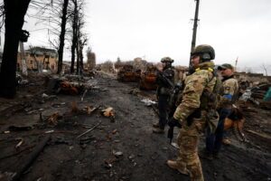 Soldiers walk to see destroyed Russian military vehicles, amid Russia’s invasion on Ukraine in Bucha, in Kyiv region