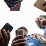Group in a circle holding mobile phones viewed from the ground up