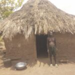 Uguru standing in front of his hut