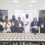Ndidi (fourth from left) with guests displaying copies of her book during the programme