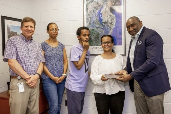 Ike Ogbuebile presenting an iPad to a parent and a child on the autism spectrum.