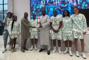 Carloha Nigeria MD, Mr. Sola Adigun, NFF President, Alhaji Ibrahim Musa Gasau (wearing a cap), and the Super Falcons players, show off the WAFCON trophy at the Chery showroom in Alapere, Lagos, recently