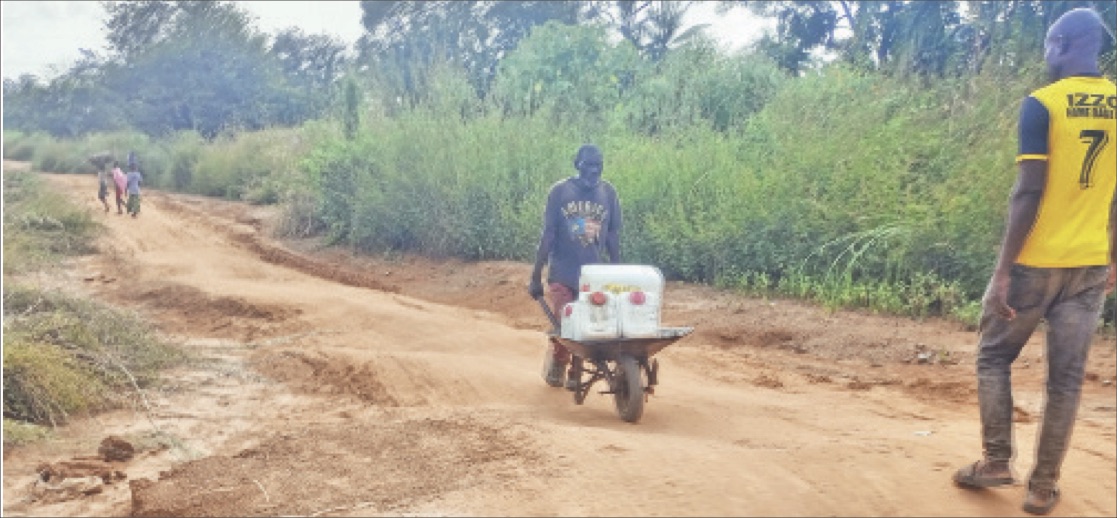 An elderly man returning from where he went to fetch water far from the community