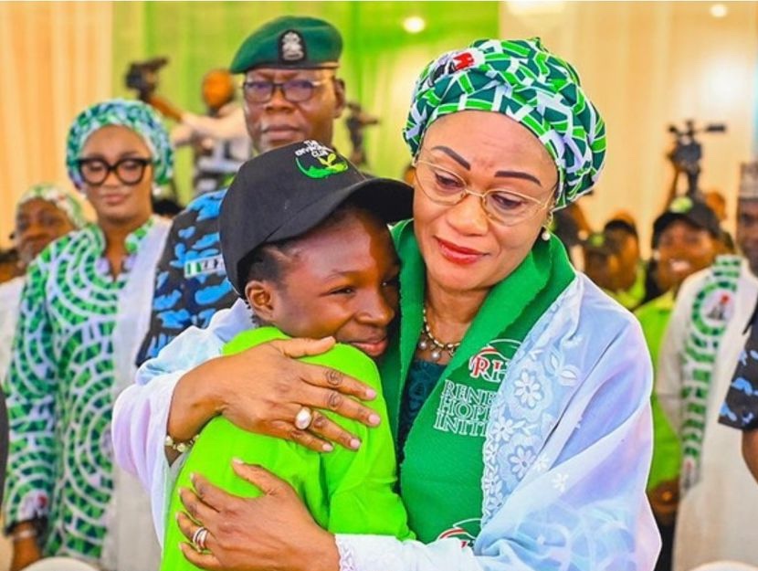 First Lady, Oluremi Tinubu in a warm embrace with Esther Abraham, a poet and Senior Secondary 3 student from Government Senior Secondary School, Mabushi