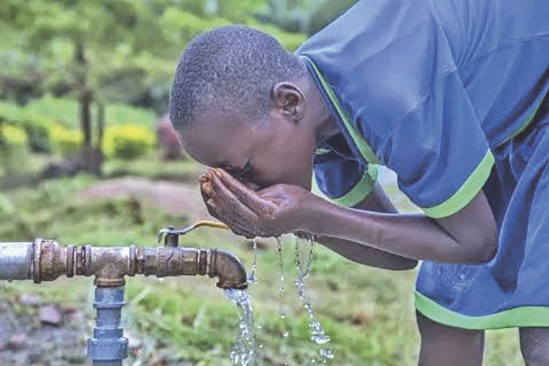 A kid drinking water from a tap