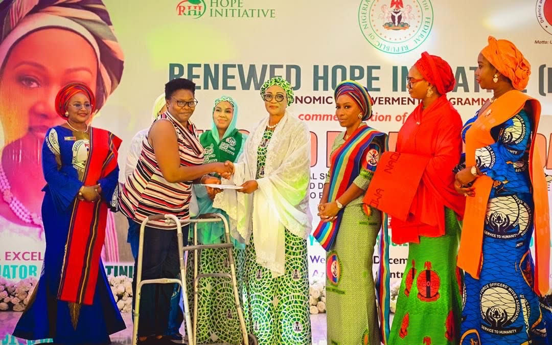L-R Wife of the IGP, Elizabeth Egbetokun, Wife of the Chief of Naval Staff, Aisha Abbas, Wife of the Deputy Senate President, Laila Barau, First Lady of Nigeria, Oluremi Tinubu, Wife of the Chief of Defence Staff, Mrs Mernan Oluyede and the Wife of the Chief of Army Staff, Safiyyah Shaibu while the First Lady presents financial support to one of the 250 Disabled Veterans from the Military and Police in Abuja on 3rd Wednesday 2025