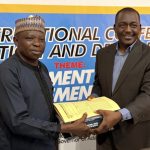 Seamless Transition at NSUK ISDEVCOM: Pioneer Executive Director Professor Emmanuel Dandaura (right) hands over to Acting Director Dr. Daniel Chikada during Friday’s boardroom ceremony in Keffi, attended by HODs, scholars, and alumni