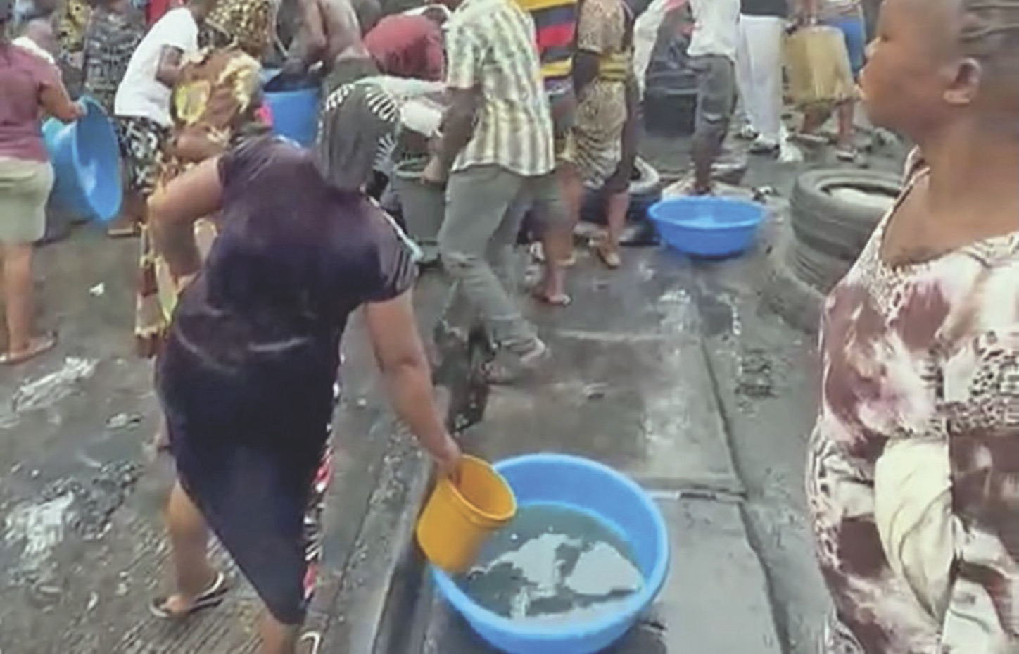 People scooping fuel from a fallen tanker