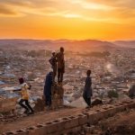 Men look at the sunset on the top of Zinariya hills, in Jos, on February 28, 2025