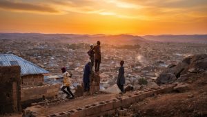 Men look at the sunset on the top of Zinariya hills, in Jos, on February 28, 2025