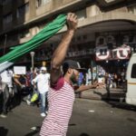 A man runs holding a Nigerian flag as thousands march against the recent wave of xenophobic attacks in South Africa through the streets of Johannesburg CBD on April 23, 2015. Several thousand demonstrators marched through central Johannesburg on Thursday to protest against a spate of deadly attacks on immigrants, after further raids by the authorities on suspected gang hideouts. Watched by police, crowds sang songs denouncing xenophobia and carried banners that read “We are all Africans” as migrant workers crowded balconies, shouting their support. AFP PHOTO/GIANLUIGI GUERCIA (Photo credit should read GIANLUIGI GUERCIA/AFP via Getty Images)
