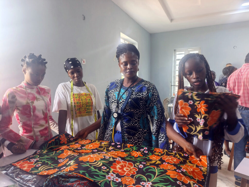 Some of the students of the centre receiving practical instruction in fabric measurement, pattern layout and material selection during a fashion design training session