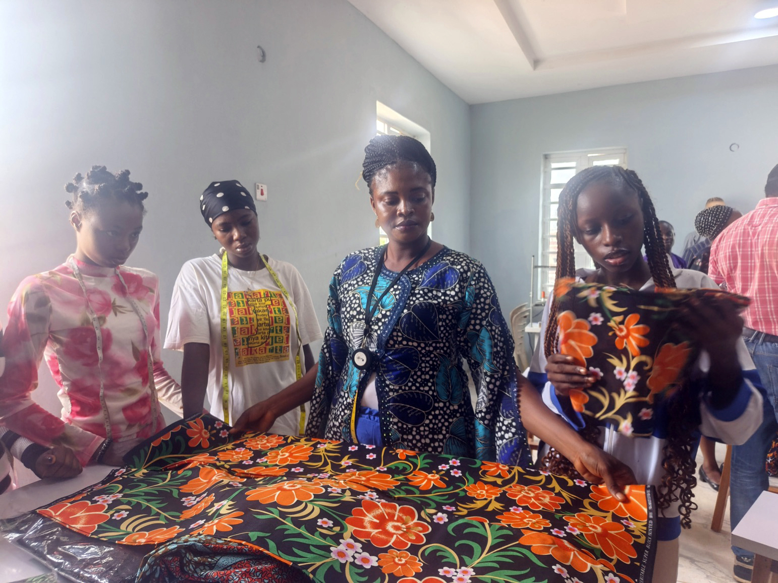 Some of the students of the centre receiving practical instruction in fabric measurement, pattern layout and material selection during a fashion design training session