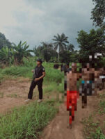 Policemen leading the suspects out from the forest