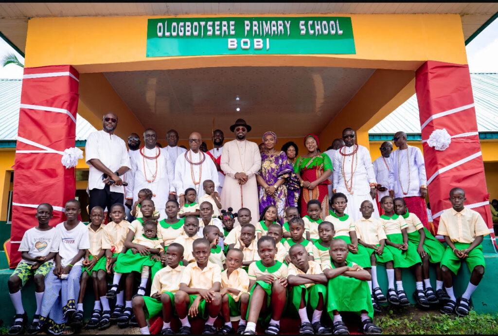 The Olu of Warri, Ogiame Atuwatse III, and his wife, Her Majesty Olori Atuwatse III, surrounded by some Itsekiri traditional chiefs and pupils of Ologbosere Primary School in Bobi, Warri South-West Local Government area during the commissioning