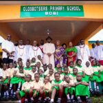 The Olu of Warri, Ogiame Atuwatse III, and his wife, Her Majesty Olori Atuwatse III, surrounded by some Itsekiri traditional chiefs and pupils of Ologbosere Primary School in Bobi, Warri South-West Local Government area during the commissioning