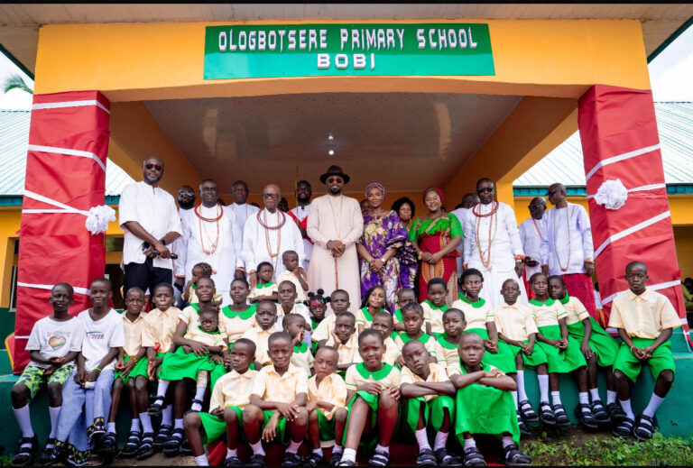 The Olu of Warri, Ogiame Atuwatse III, and his wife, Her Majesty Olori Atuwatse III, surrounded by some Itsekiri traditional chiefs and pupils of Ologbosere Primary School in Bobi, Warri South-West Local Government area during the commissioning