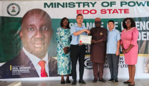 The Commissioner for Power, Hon. Paul Usenbo, presenting the Certificate to the management of the company
